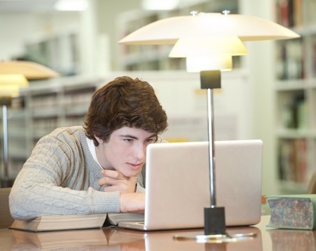 Male student using laptop computer in library