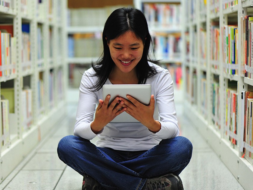 照片：在图书馆使用平板电脑的年轻女子
