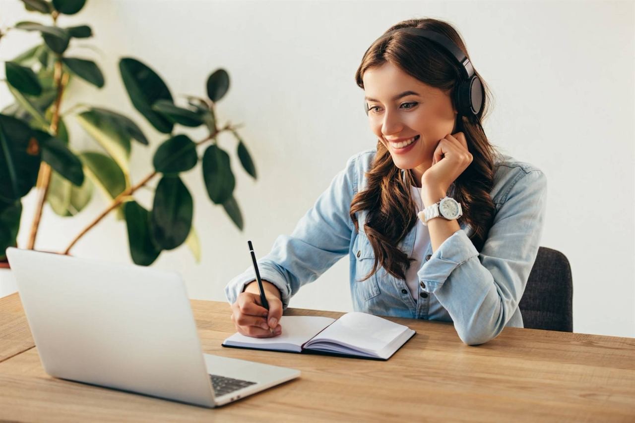 Teilnehmerin mit Kopfhörern verfolgt ein Webinar am Laptop