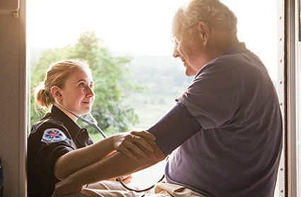 We connect people to the information they need. Female medical technician attends elderly man