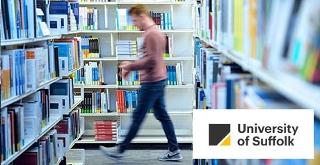 Library patron walking through shelves of books in a library