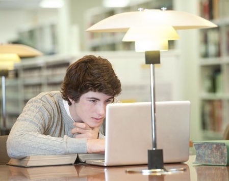Let patrons manage their ILL experience Male student using laptop computer in library