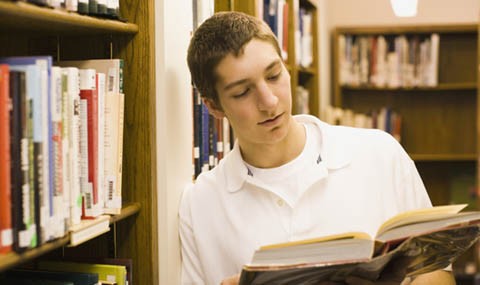 Photo of student reading a book in a library