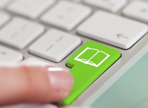 Teclado de computadora con una tecla de color verde que muestra el icono de un libro