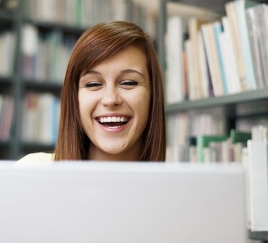 Persona sonriente usando una computadora en la biblioteca