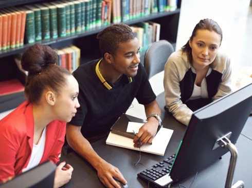 Estudiantes usando una computadora en la biblioteca