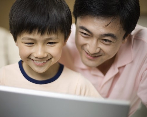 Padre e hijo mirando una computadora portátil