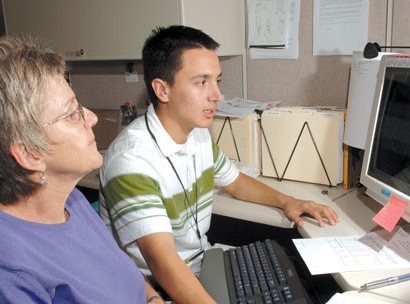 Optimice los procesos de catalogación original y copiada para compartir registros con las bibliotecas miembro de OCLC Dos bibliotecarios usando una computadora