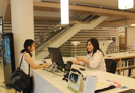 Estudiante y bibliotecaria en el mostrador de circulación de la biblioteca de ADA University