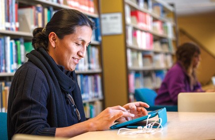 Une personne utilise un ordinateur tablette dans une bibliothèque