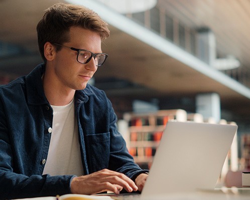 Homme utilisant un ordinateur portable dans une bibliothèque